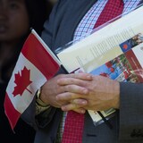 Isang tao na hawak ang Canadian flag, citizenship certificate at isang liham mula kay Prime Minister Justin Trudeau.
