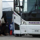 لاجئون أفغان ومواطنون كنديون يصعدون إلى حافلة ركاب في مطار بيسرون الدولي في آب (أغسطس) 2021. 