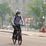 A cyclist wears a mask during poor air quality conditions as smoke from wildfires in Ontario and Quebec hangs over Ottawa on Tuesday.