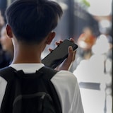 Un élève écoute son cellulaire devant la fenêtre d'une école (Photo d'archives)