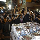 Des journalistes prennent en photo des piles de journaux.