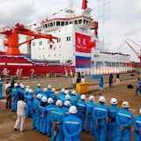 Workers gathered next to a large vessel.