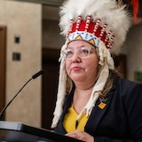 La cheffe nationale de l’APN, Cindy Woodhouse Nepinak portant une coiffe traditionnelle autochtone pendant un discours.