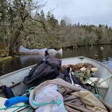 Un bateau est rempli de matériel de pêche illégal. Un agent de Pêches et Océans Canada est dans l'eau en train d'inspecter un filet.