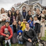 Dix adultes, neuf enfants et un chien devant une résidence.