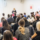 Une conférencière fait une présentation devant une foule de quelques dizaines de participants.