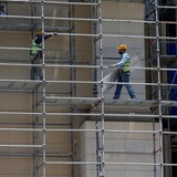 Deux travailleurs de la construction circulent sur un échafaudage le long d'un édifice.