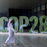 Isang lalaki naglalakad sa harap ng sign na #COP28.