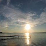 Un quai sur le bord d'un lac dont le soleil se reflète sur la surface.