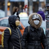 People wearing masks as a countermeasure to COVID-19 walk through the snow in Toronto on Dec. 8, 2021. Two years into the global coronavirus pandemic, Canadians are weary and want to know when they can get more normalcy back.