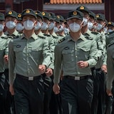 Chinese People's Liberation Army (PLA) soldiers wearing protective face masks march past the entrance to the Forbidden City in 2020. 