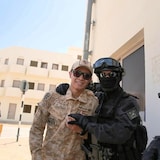 A man in military fatigues with policemen in tactical gear.