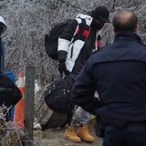 اثنان من طالبي اللجوء يدخلون إلى كندا بشكل غير نظامي عبر طريق روكسهام في 5 كانون الثاني (يناير) 2023 تحت أنظار ضابط في الشرطة الملكية الكندية.