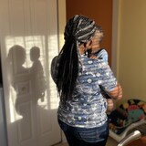  Une femme de dos tient son enfant dans ses bras, leur silhouette se découpe sur la porte.