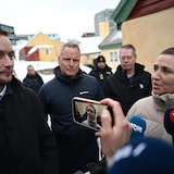 A man and woman speak to reporters outside.