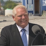 Doug Ford sourit derrière un podium sur un chantier de construction.