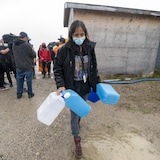 Una mujer indígena transporta bidones de agua.