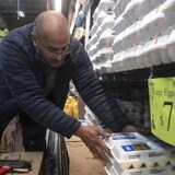 A worker stocks eggs on a shelf at a grocery store in Detroit, Mich., last month. Egg prices across the U.S increased by 60 per cent in the last year. That's about four times the increase of prices in Canada, but prices were higher in Canada to begin with. (Matthew Hatcher/Bloomberg)
