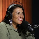 A woman wearing earphones and talking into a microphone. 