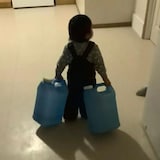Un enfant transporte des bidons d'eau.