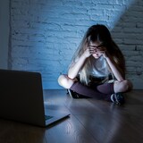 Fille effrayée, victime de cyberintimidation et de harcèlement en ligne avec son ordinateur portable.