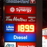 Un panneau publicitaire éclairé, la nuit, dans une station-service, affichant le litre d'ordinaire à 1,89 $.