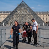Firefighters from the Paris Fire Brigade escort a person outside the Louvre Museum during an intense heat wave on Thursday. French authorities announced a ban on drinking alcohol in public on Friday, as concern amid the heat wave persisted. 