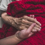 Une infirmière tenant la main d'un patient âgé.