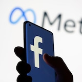 Un téléphone cellulaire dans une main arbore le logo de Facebook.