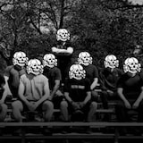 A group picture in black and white of people dressed in active clothes with skull images hiding their faces.