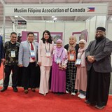 Isang grupo ng mga lalaki at babae sa harap ng booth ng Muslim Filipino Association of Canada sa loob ng expo.