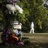 A crime scene investigator in Weldon, Saskatchewan, with a bouquet of flowers in memory of a victim of the September 4, 2022 knife attacks.