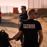 Reporters in press vests at a checkpoint.