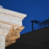 De la fumée noire s'élève de la cheminée de la chapelle Sixtine, dans la nuit au Vatican.