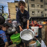 Niños palestinos esperan recibir un plato de comida en Gaza.