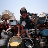 فلسطينيون ينتظرون الحصول على الطعام من مطبخ مجتمعي في مدينة غزة، في 26 تموز (يوليو) 2025.