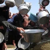 Des gens tendent des casseroles désespérément pour obtenir de la nourriture.