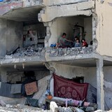 Un palestino y sus hijos sentados en una habitación destruida tras un ataque aéreo israelí.