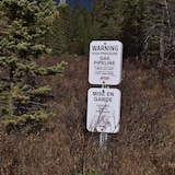 Une affiche annonce le passage d'un gazoduc exploité par la compagnie ATCO sur un terrain boisé, près de Jasper, dans l'Ouest canadien.