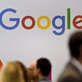 Des gens passent devant un logo de Google.