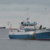 A boat sails in the water with a Nunavut and Canadian flag. 