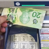 A man withdraws a $20 bill from an ATM.