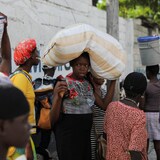Une jeune femme avec un sac sur la tête, au milieu de la rue.