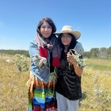 Two people holding plants in a field.