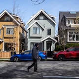 A man walks past houses in Vancouver, which is expected to be overtaken by the Greater Toronto Area in 2024 as the city with the highest home prices, according to a new report from Royal LePage. 