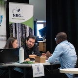 Trois personnes, dont un candidat et deux recruteurs, participent à un entretien d'embauche.