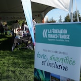 Un panneau de la Fédération franco-ténoise devant une tente abritant des exposants.