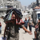 A displaced Palestinian carries belongings, as he flees amid an Israeli military operation, in Gaza City on Monday. Israel's push into Gaza City comes as leading genocide scholars issue a resolution that the legal criteria has been met to declare Israel's actions in Gaza a genocide. 