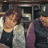 Une femme lit un document, un homme à ses côtés regarde le même document. 