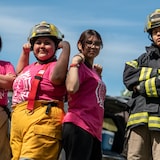 Quatre jeunes femmes autochtones en uniforme de pompière participent à un exercice de formation.